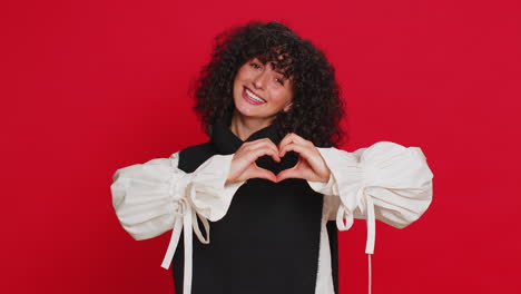 joven sonriente hace un gesto de corazón demuestra un signo de amor expresa buenos sentimientos y simpatía