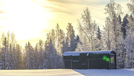 fiery sunset over thickly snow-covered forest with thermowood cabin