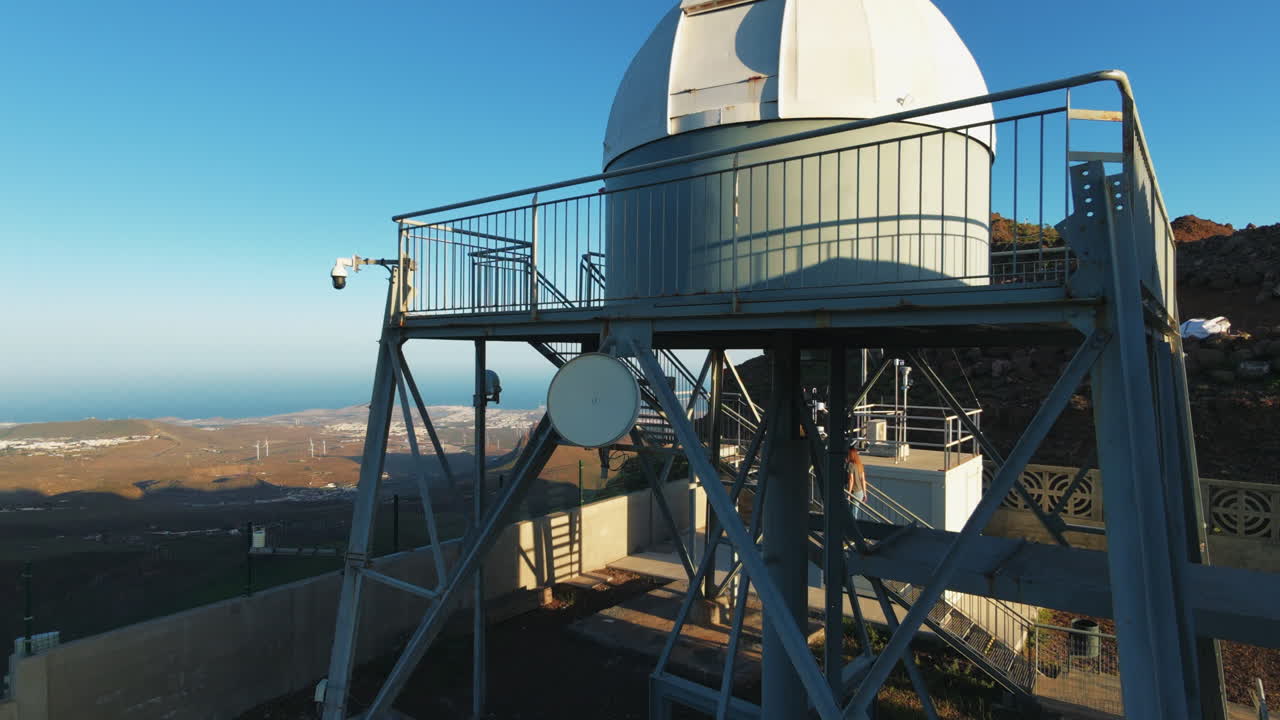 Vista aérea ascendente de um observatório astronômico profissional com uma cúpula giratória em um pico de montanha vulcânica alta com vista para o oceano