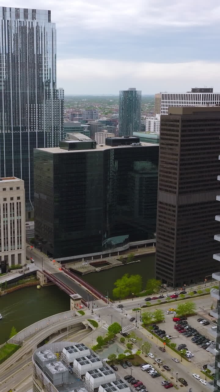 Land and water transport moving among the buildings of Chicago. Urban scenery of modern metropolis at daytime. Top view. Vertical video