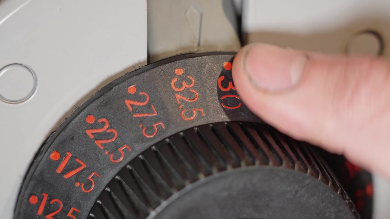 Close up of an adjustable dumbbell showing weight increased from 20 kilograms to 32 kg by a male hand