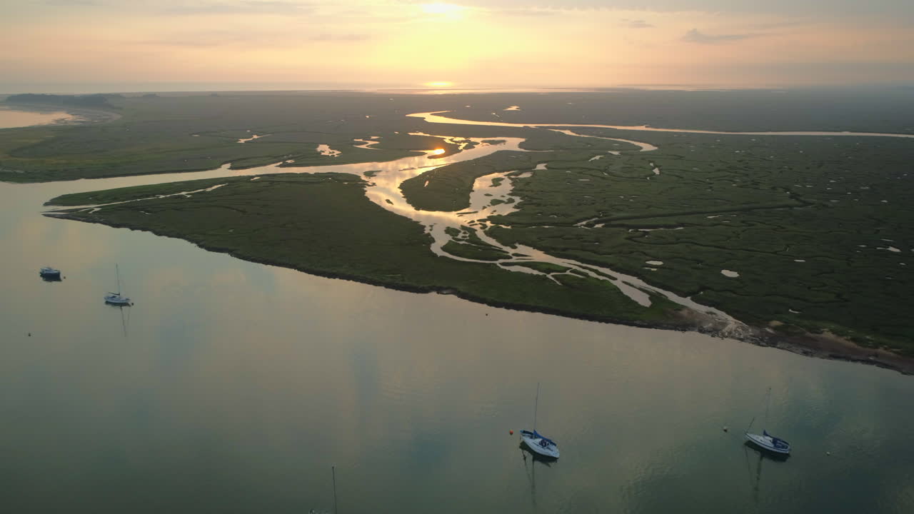 만조 때 만조 때 개울과 염습지 위로 높은 드론 샷, 아름다운 일출과 바다 북부 노퍽 영국 동부 해안의 반사
