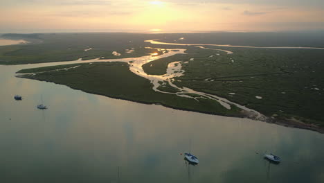 high drone shot over creek and salt marsh at high tide with beautiful great sunrise and reflections in wells-next-the-sea north norfolk uk east coast