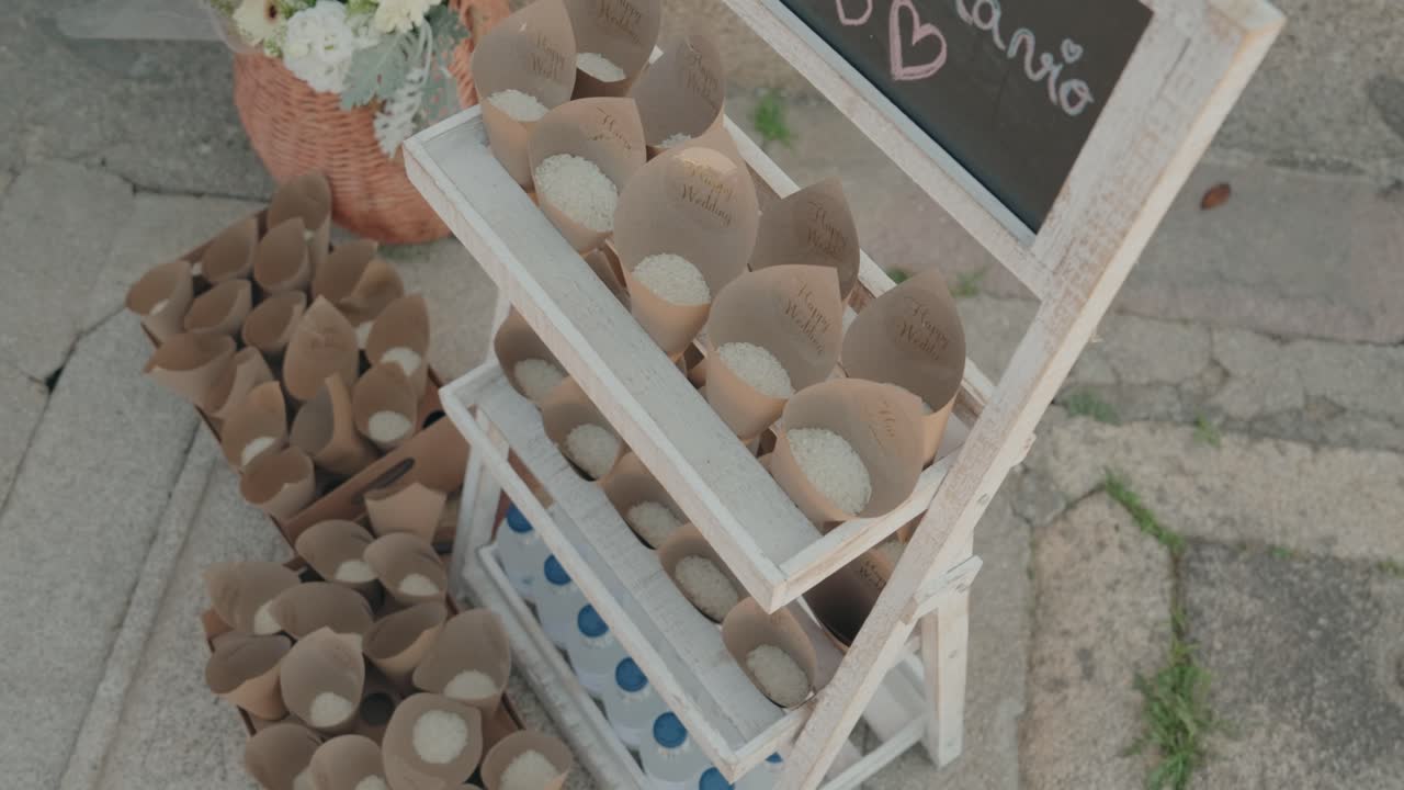 Paper cones filled with rice neatly displayed on a rustic white stand for wedding guests