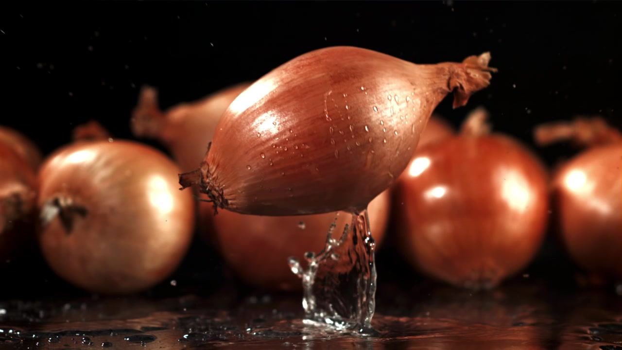 Frische Schalotte fällt in Zeitlupe mit Wasserspritzer