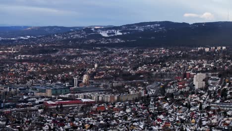 askjer oslo downtown skisenter norway norge aerial drone cityscape neighborhood apartments buildings morning winter snowing ski jump hill forelingen cloudy gray skies parallax circle right motion