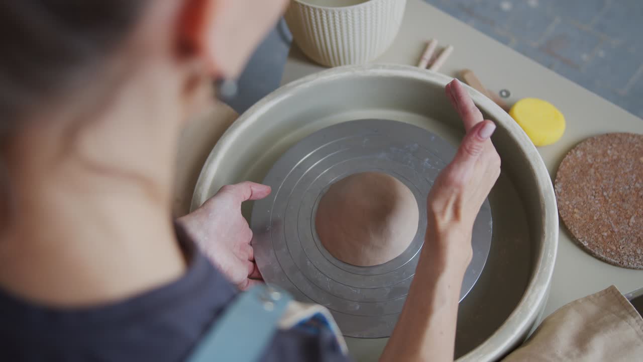 여성 도자기는 도자기 바에 점토 조각을 형성합니다.
