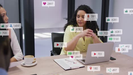 Animation-of-social-media-icons-against-biracial-woman-talking-to-diverse-colleagues-at-office