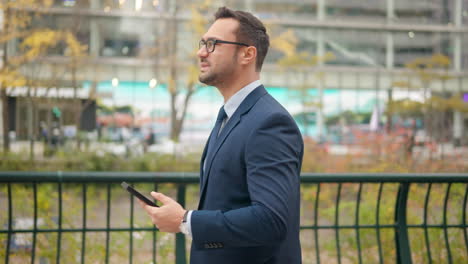 Caucasian-businessman-on-video-call-while-walking-in-city-park,-slow-tracking