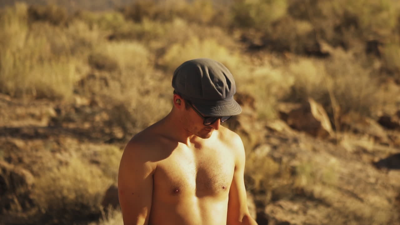 프레임 밖의 지점을 겨냥하는 두 개의 총을 들고 있는 젊은이가 와서 그의 목표를 수정