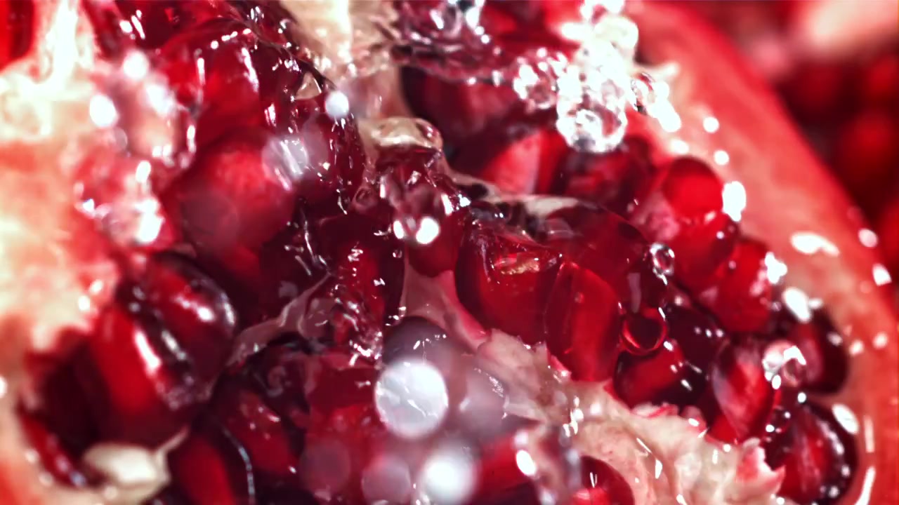 Vand sprøjter på friske granatæblekerner i slowmotion