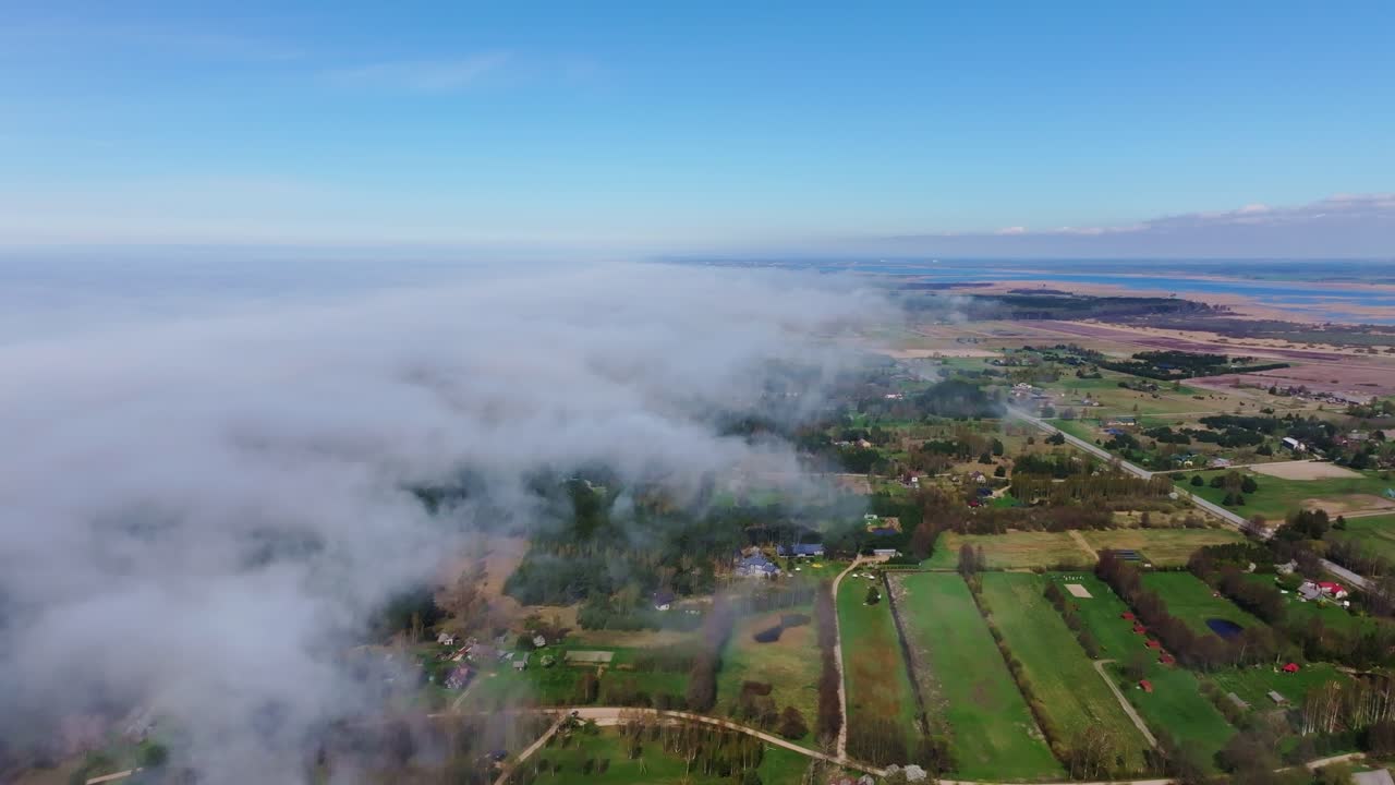 Baltic coastal mist slowly moves across green farmland and villages