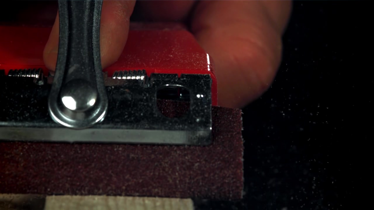 Close-up of Hand Sanding Wood with a Red Sanding Block