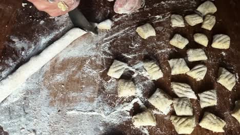 Küchentisch-Gefüllt-Mit-Gnocchi-Nudelzubereitung,-Küchenchefhände,-Nahaufnahme-Italienischer-Küche,-Traditionelle-Pasta,-Zeitlupenmesser-Zum-Schneiden-Von-Mehlteig