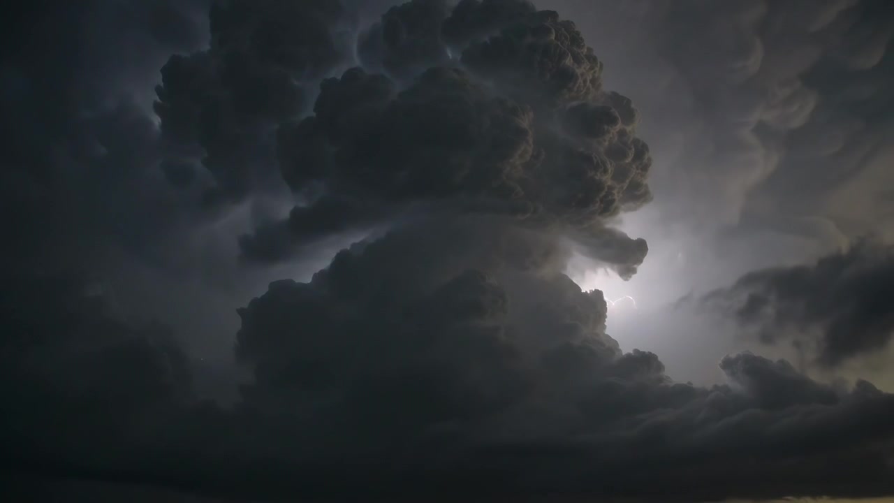 Flashing internal lightning illuminating thundercloud over low horizon, revealing turrets