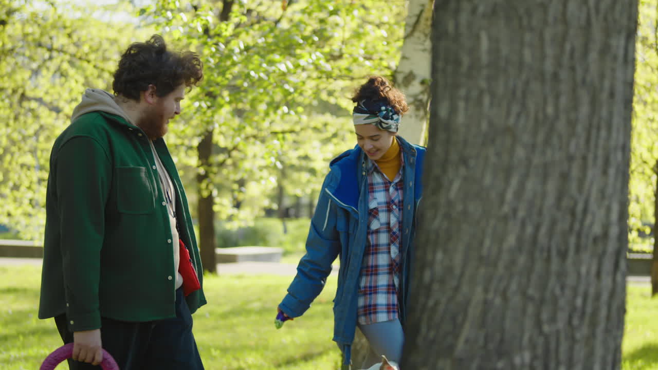Couple walks their dogs in a sunny park