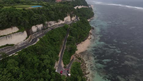 vista aérea, carretera de asfalto a orillas de acantilados y mar ubicada en la playa de tanah barak, isla de bali, indonesia