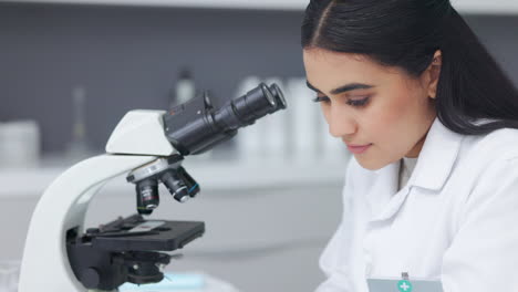 Científico-Femenino-Usando-Un-Microscopio-En-Una-Investigación
