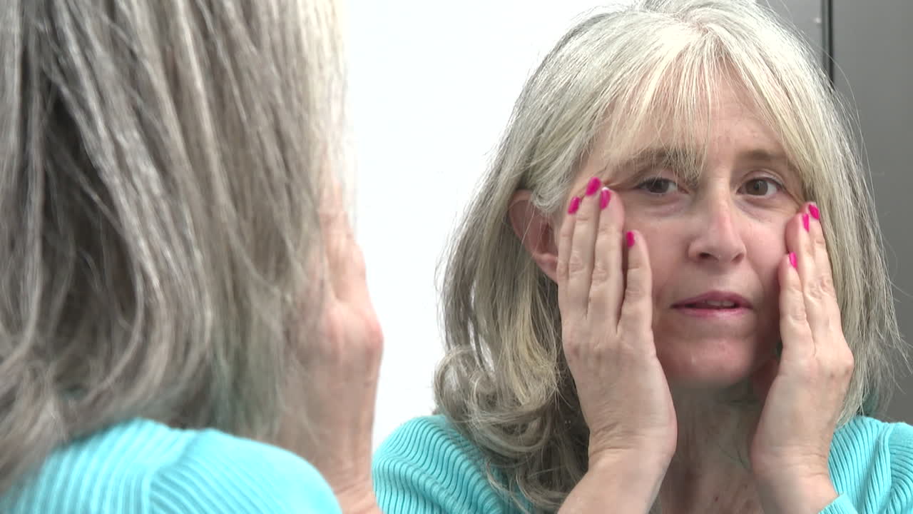 Kvinde lægger makeup på foran et spejl