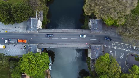 Aerial-of-directed-traffic-crossing-a-traditional-old-toll-bridge-across-a-quaint-river