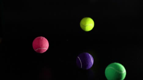 various colored tennis balls bouncing in darkness