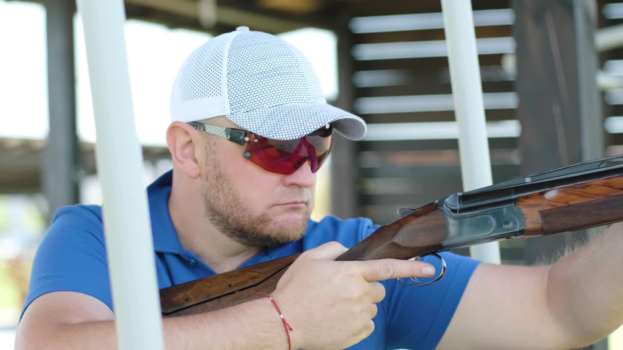 스포츠맨이 이중 배럴 건으로 총을 고, 슈팅 테스트를 위한 스포츠 경기장은 날아다니는 스케이트를 고 있습니다.