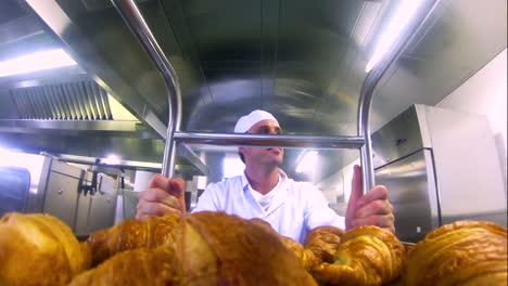 young baker pushing a trolley of croissants