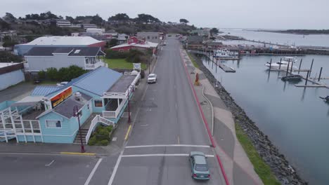 aerial dolly along coastal road fronting harbor as car comes into view