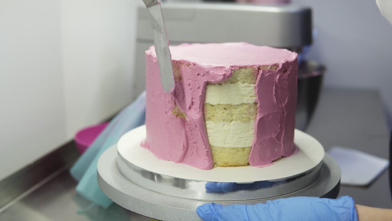 The process of decorating a cake with purple cream cover. Confectioner equates biscuit cream using pastry spatula