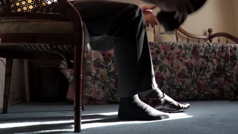 man putting on dress shoes in the morning before work