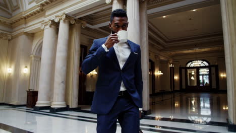 professional businessman walking in a grand hall with coffee