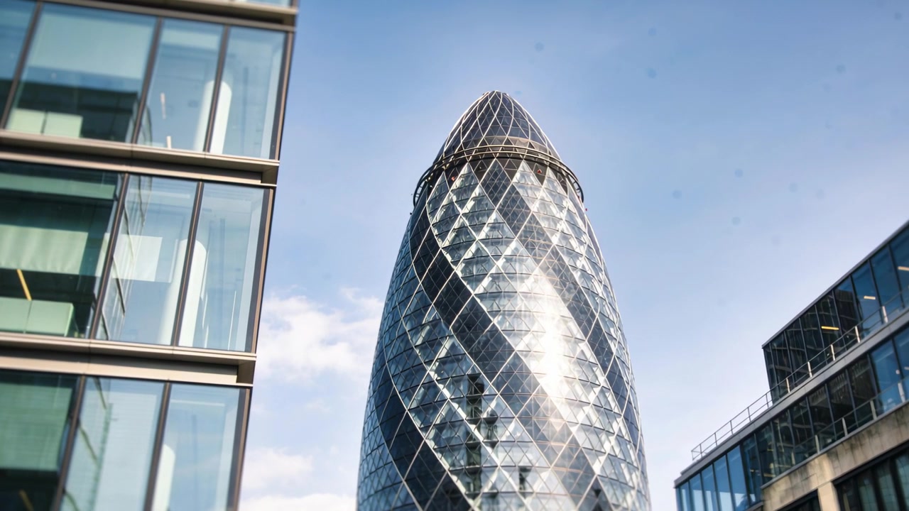 Telecamera che si inclina, catturando la torre Gherkin che si erge nel centro città, rivelando la cima a cupola e i riflessi.