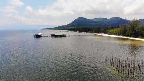 Panoramic-Aerial-View-of-Fishing-Coastal-Village-in-Phu-Quoc-island-in-South-of-Vietnam,-Wooden-Pier-Fisher-Docks-next-to-Sandy-Local-Beach