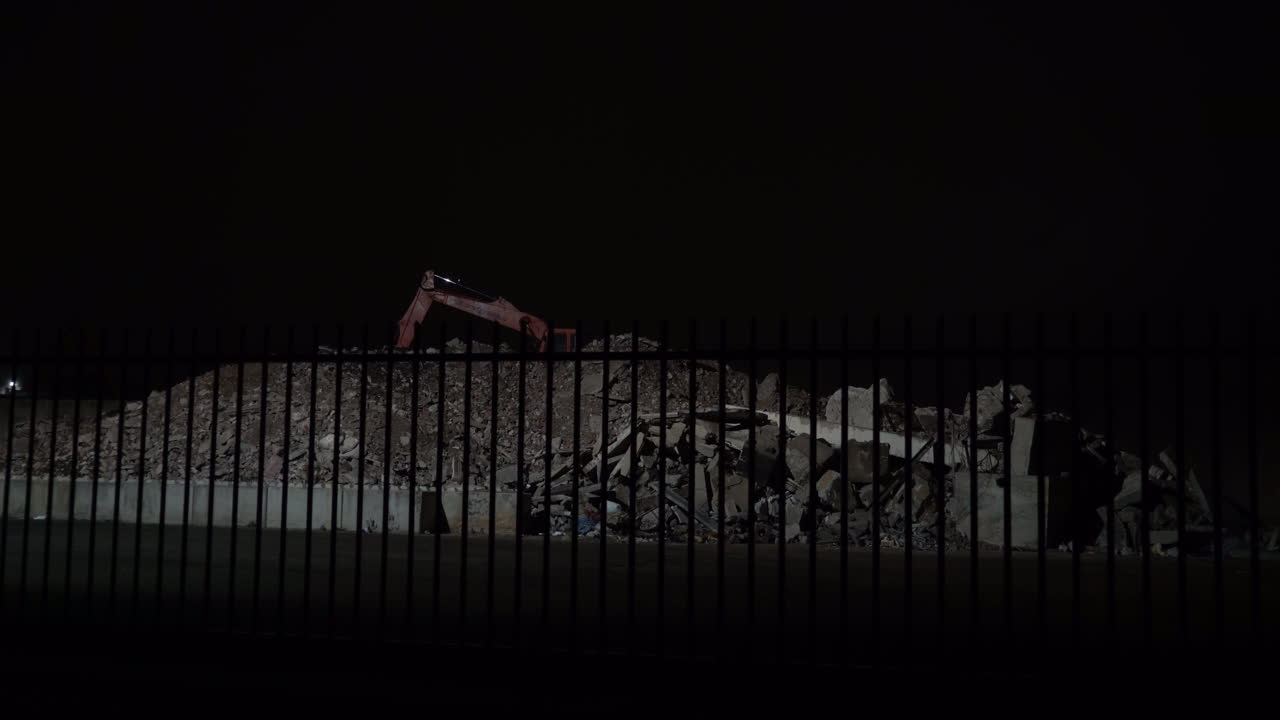 Concrete rubble and excavator at night - wide