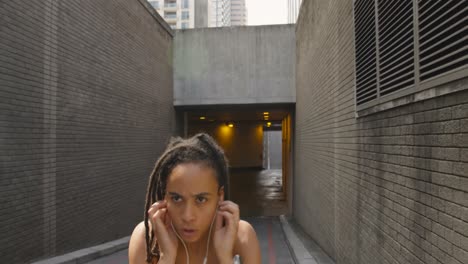 vista frontal de una mujer afroamericana corriendo en la ciudad 4k