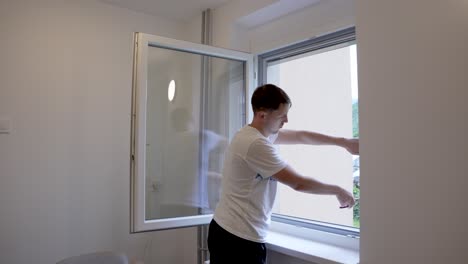 diy project: man fits a framed fixed mosquito net onto a window for insect protection
