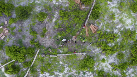 African-kids-running-around-man-operating-drone-in-rainforest-clearing