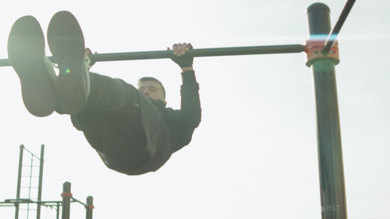 спортсмен делает передний рычаг на бар на тренировочной площадке