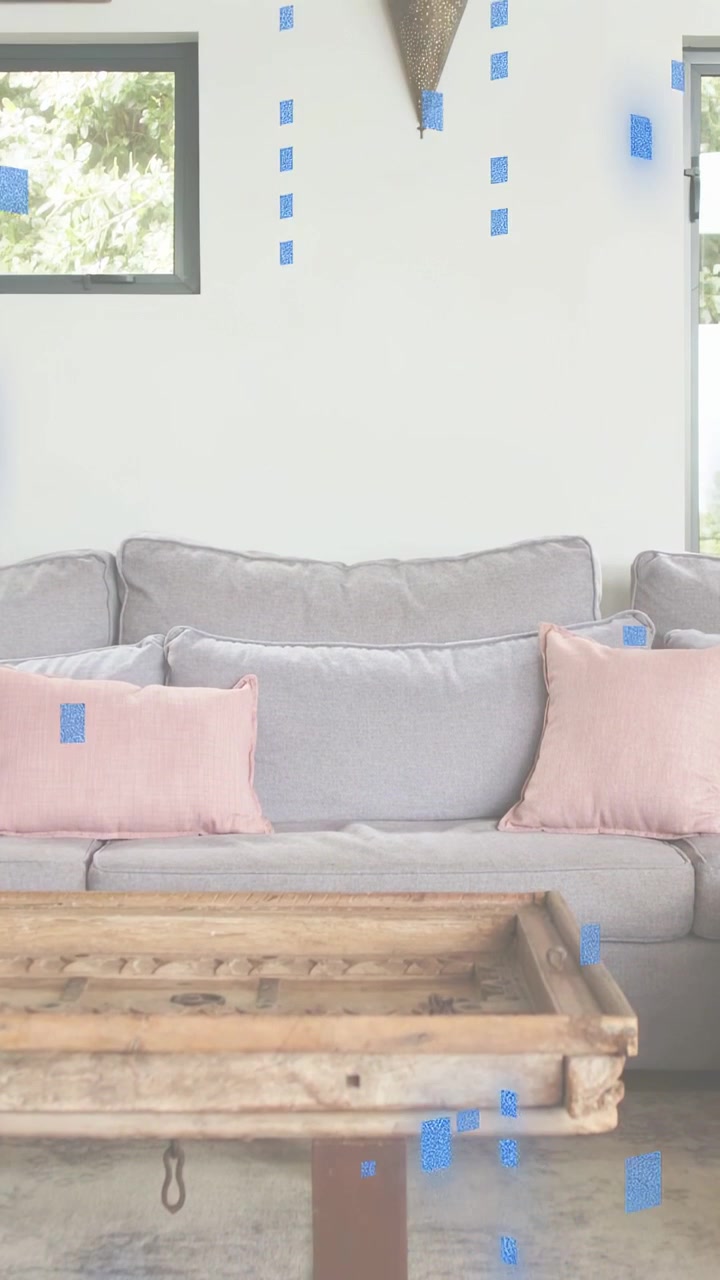 Vertical video: Blue tiles starting at cushion, clustering, drifting over gray sofa to show overlay