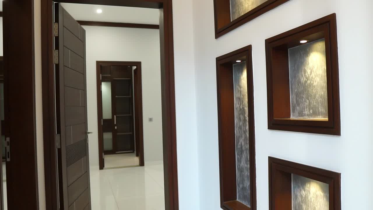 muévase hacia atrás a lo largo del pasillo recortado de madera oscura con la puerta abierta a la vista