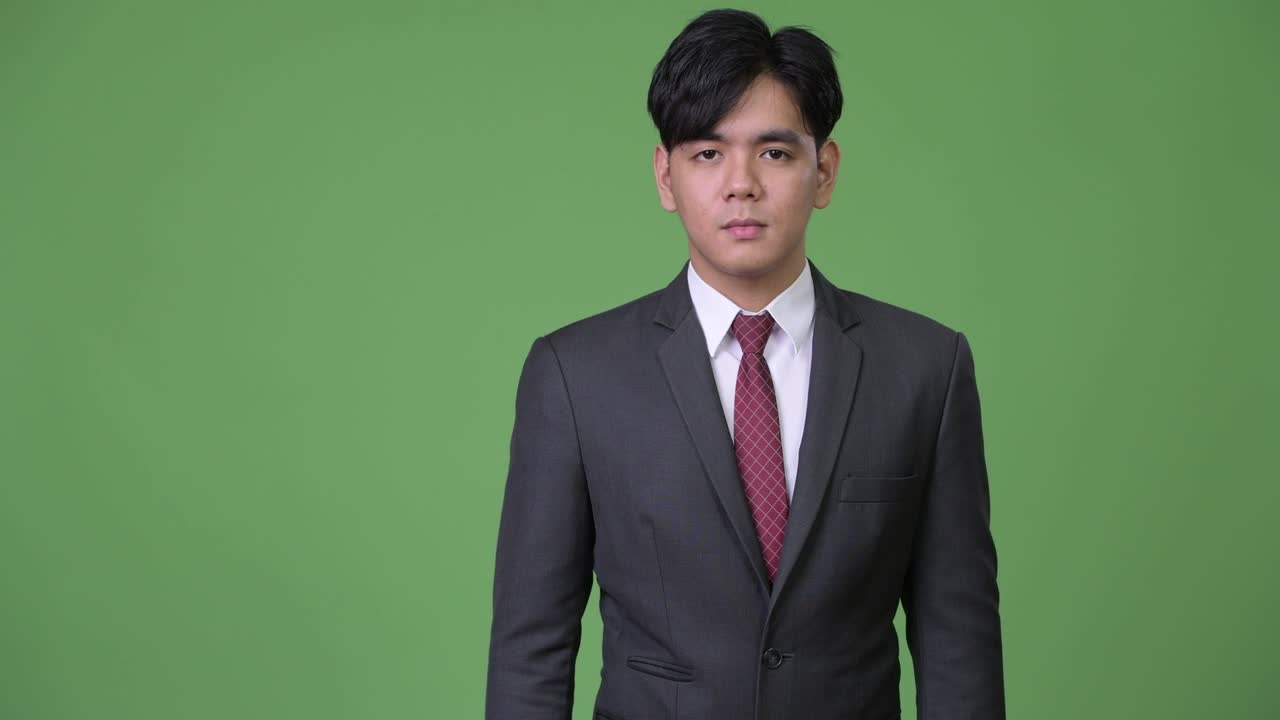 젊은 잘생긴 아시아 사업가가가 엄지손가락을 올리고 있습니다.