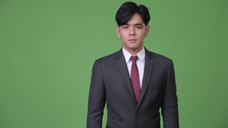 joven y guapo hombre de negocios asiático dando pulgares hacia arriba