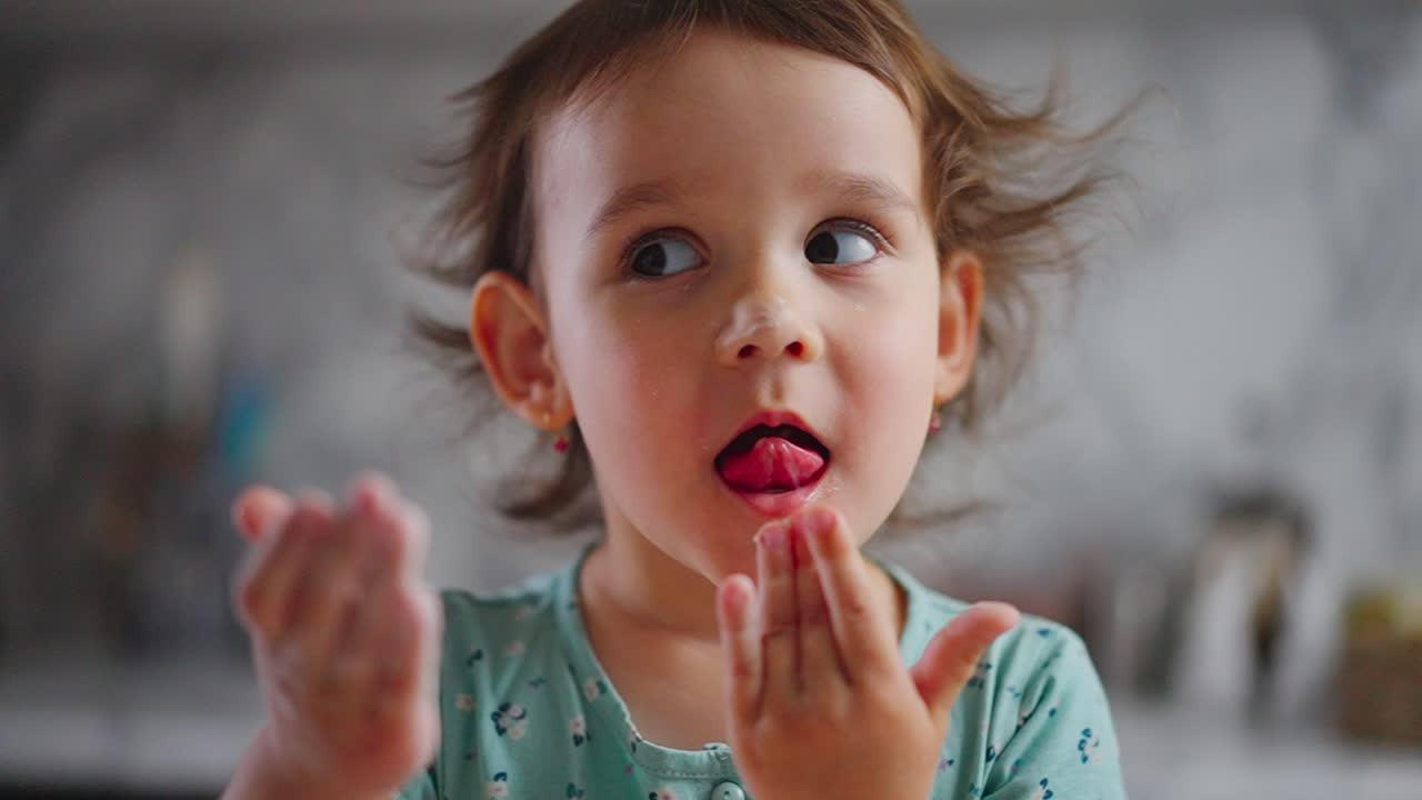 Un bambino curioso gioca con le mani in una cucina luminosa, esplorando consistenze e sensazioni con un'espressione giocosa di meraviglia e gioia