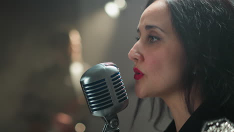 intenso primer plano de una vocalista femenina cantando en un micrófono vintage, ambientado contra un fondo suavemente borroso