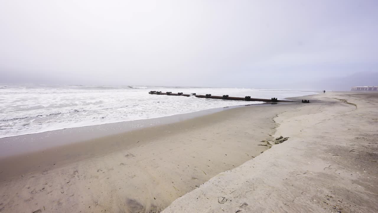 Wide view of rough waves ocean approaching camera on beach on a gloomy day in OCNJ