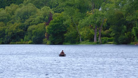 distant view of a man float tube fishing over tranquil lake. aerial slow motion shot
