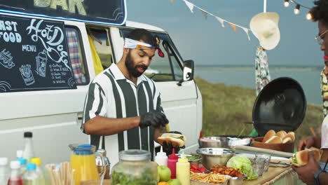 Vendedor-De-Camiones-De-Comida-Preparando-Perritos-Calientes-Y-Hablando-Con-Los-Clientes