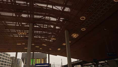 wooden ceiling at entrance to zürich railway station hb with moving light circles on a gray and cloudy winter morning.