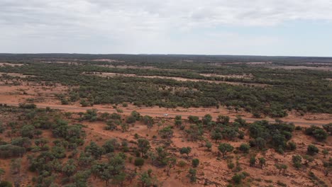 Drone-Ascendiendo-Sobre-Una-Propiedad-De-Caldera-Avanzando-Hacia-Una-Carretera-Rural-Y-Un-Automóvil-Blanco-Estacionado-En-El-Interior-De-Australia