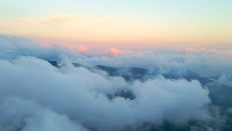 aerial view of mountains covered in clouds at sunset